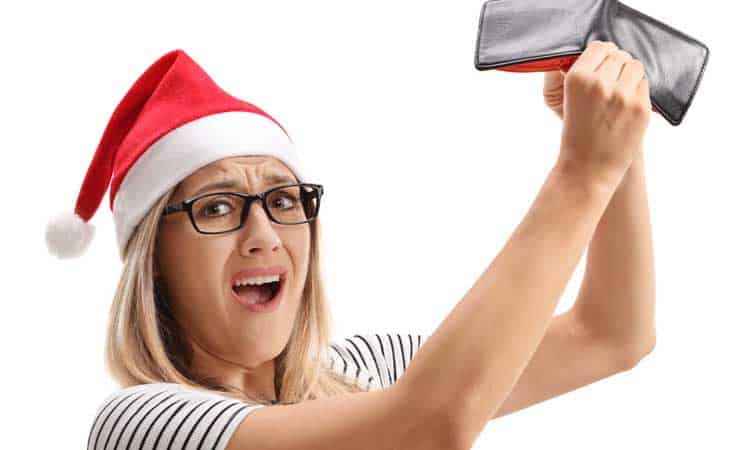 woman in santa hat holding empty wallet.
